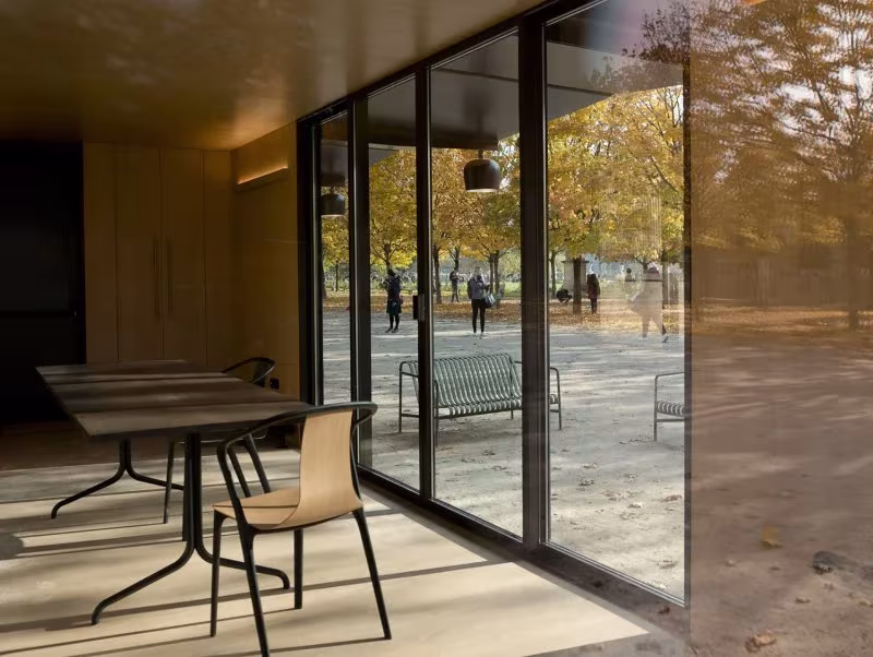 Interior del Kiosque con mesa y silla de madera frente a las cristaleras que dan al Jardín de las Tullerías