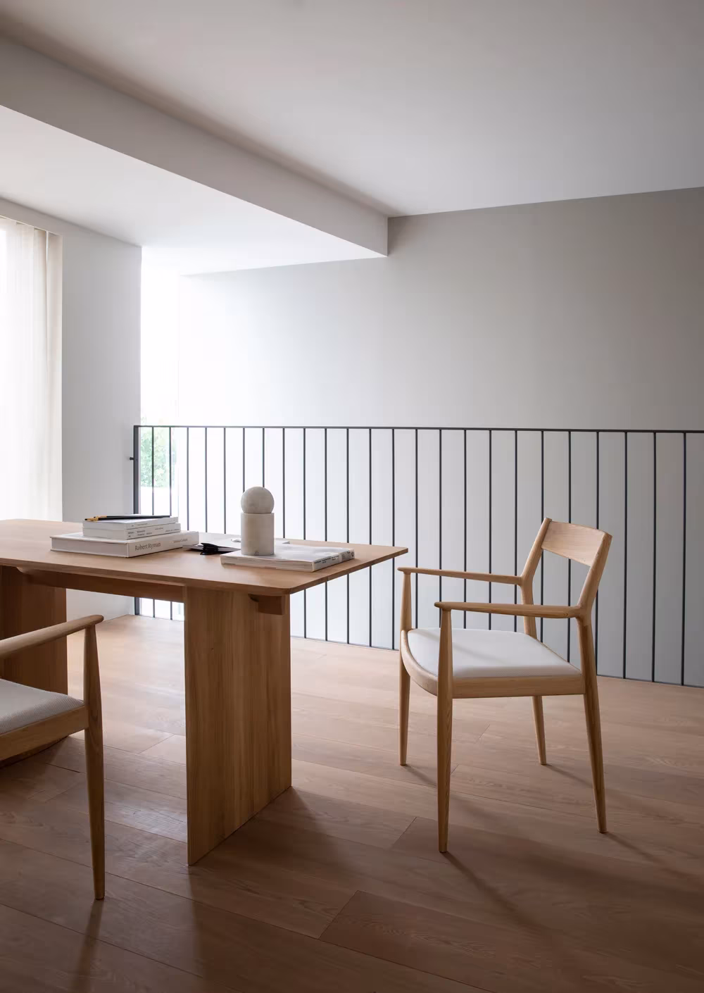 Mesa de despacho de roble con sillas y barandilla de varillas sobre la doble altura de Kinuta Terrace