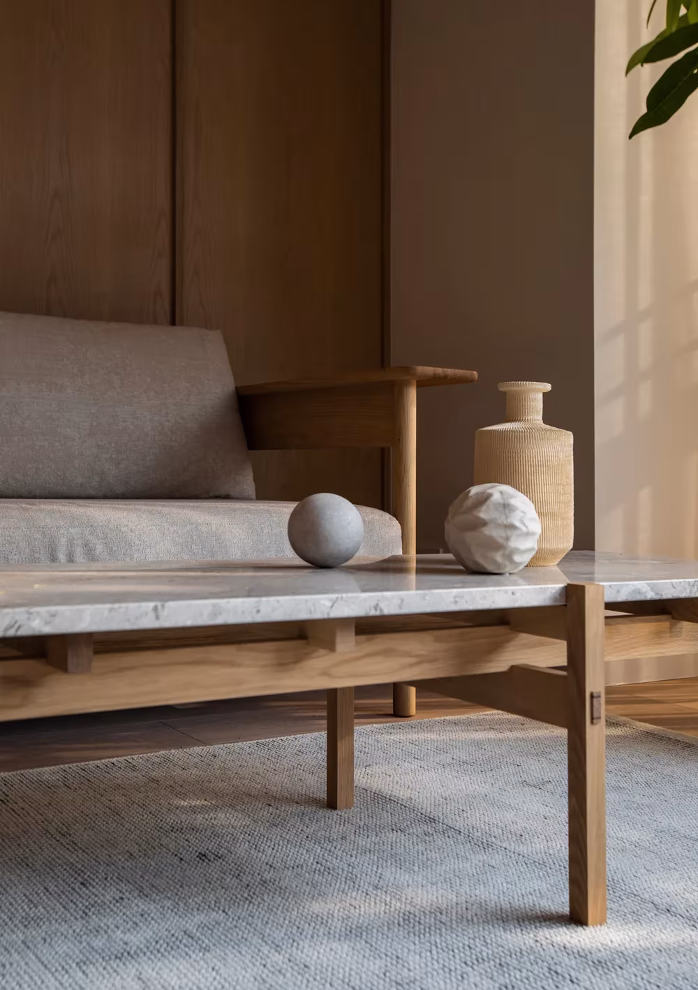 Sofá y mesa baja de roble con sobre de piedra en un apartamento de Kinuta Terrace con mobiliario a medida de Karimoku