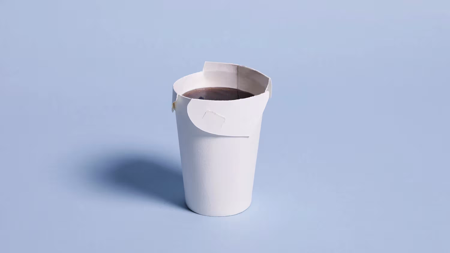 Vaso de papel Unocup con café y la tapa plegada integrada sobre un fondo azul claro