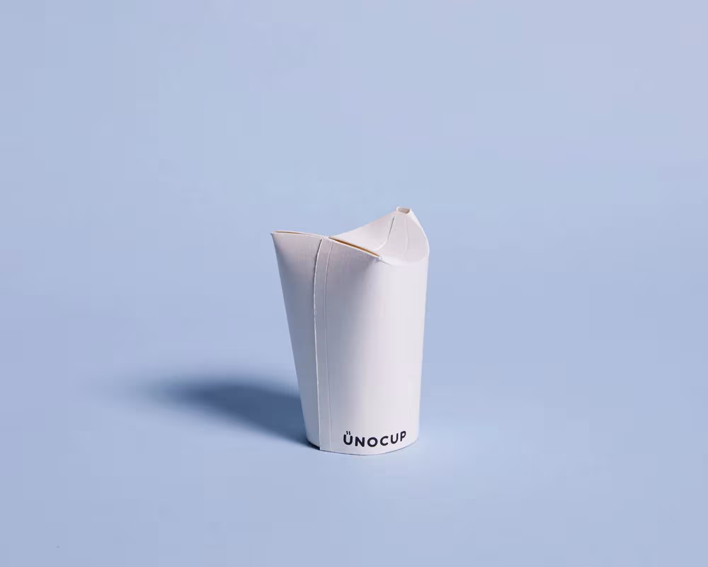 Vaso Unocup de papel blanco con la tapa plegada en forma de pétalos, de Tom Chan y Kaanur Papo
