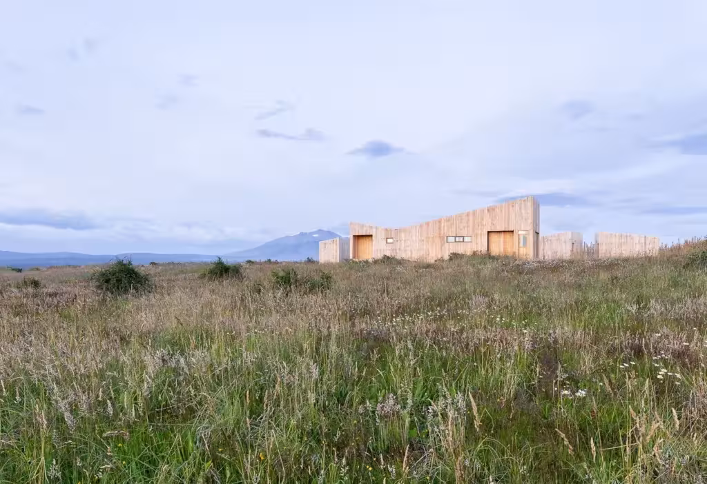 Proyecto AKA de Larrou Arq vista desde lejos con pradera delante. Hotel Boutique en Puerto Natales, Chile.