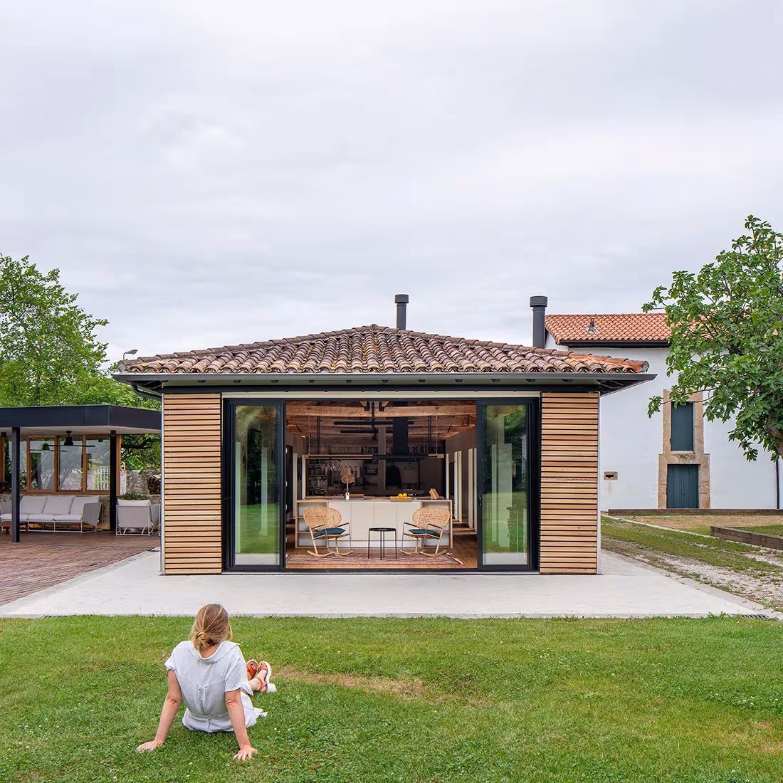 Pabellón de lamas de madera y cristal corredero abierto al jardín de la casa rehabilitada por Zooco en Güemes