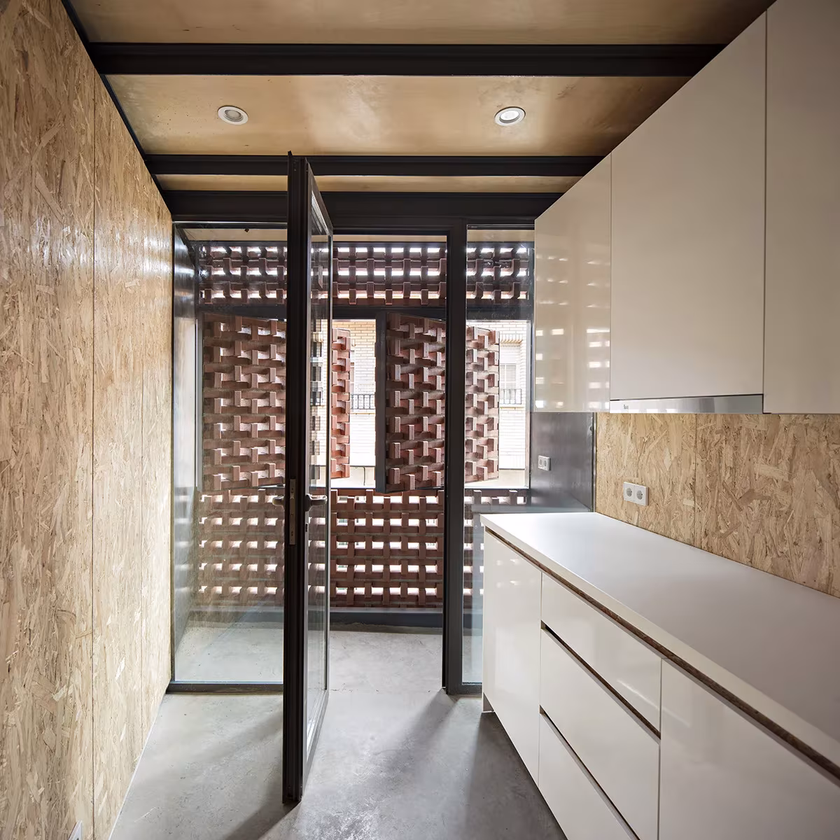Cocina blanca junto a la celosía cerámica y una puerta de vidrio con marco negro en Casa Piedrabuena