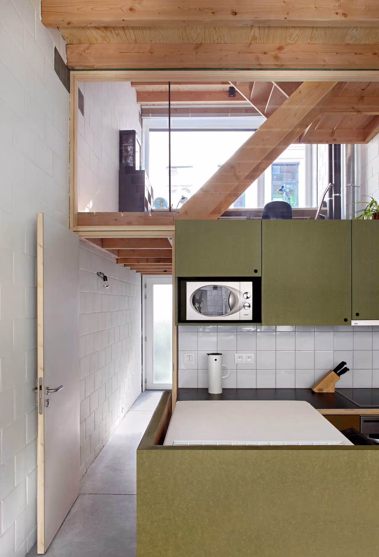 Cocina de armarios verde oliva bajo el altillo de madera de la Casa 12k de Dierendonck Blancke
