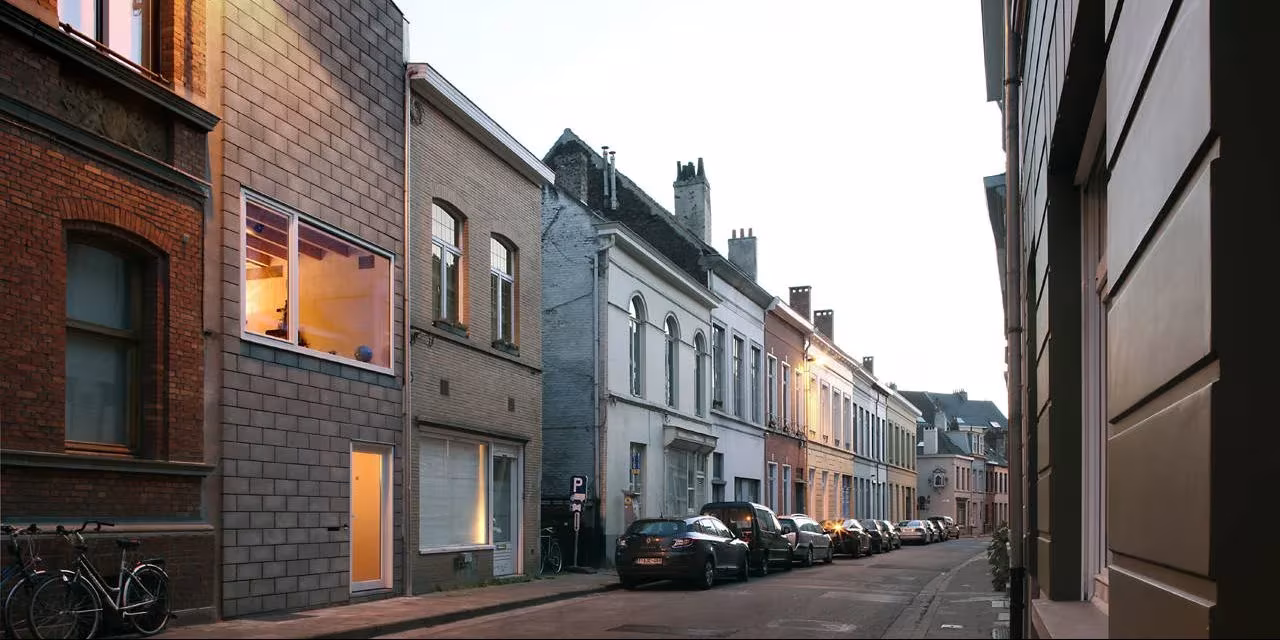 Calle del centro histórico de Gante con la fachada de bloque gris de la Casa 12k entre casas de ladrillo