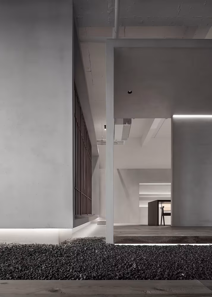 Corredor de hormigón con jardín de grava y celosía de madera al fondo en el Estudio Resee, Fuzhou