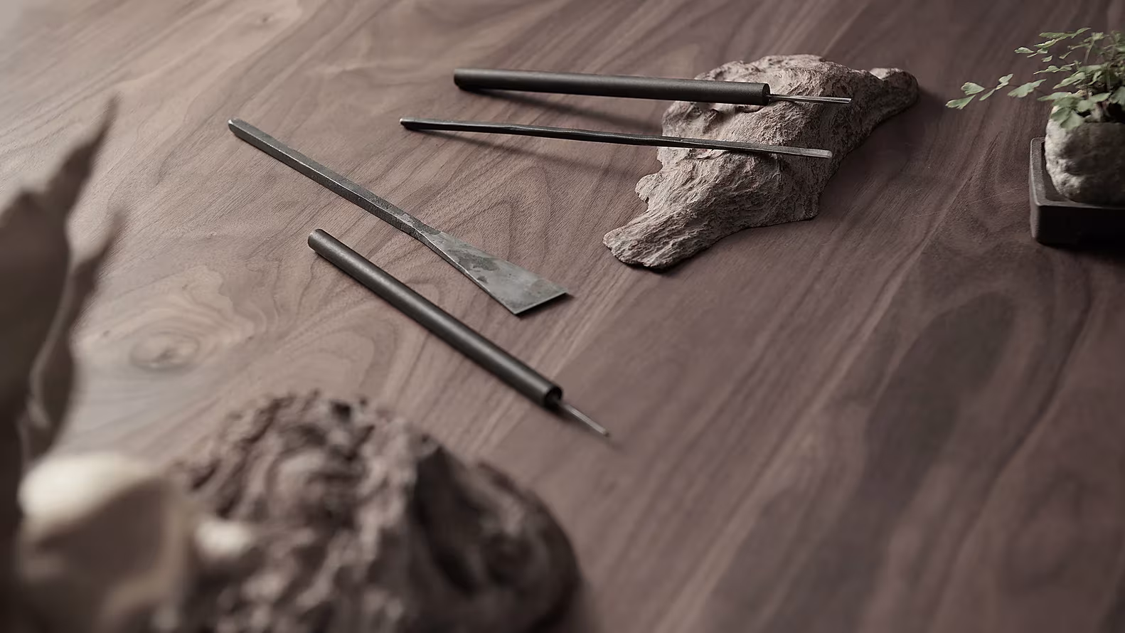 Herramientas de escultor sobre una mesa de nogal junto a piezas de madera en el Estudio Resee