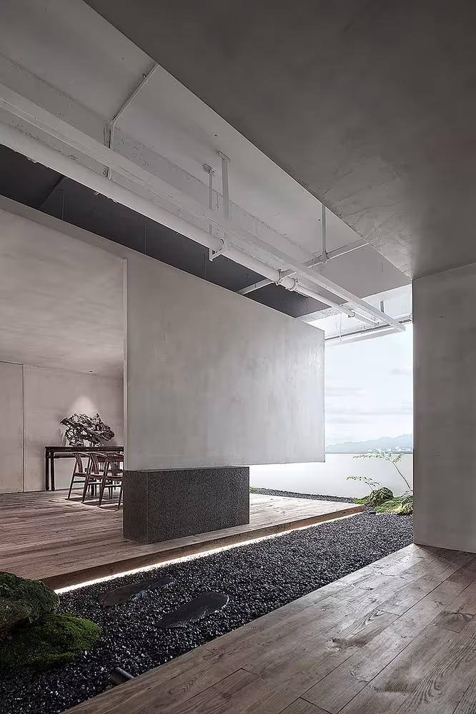 Volumen suspendido de hormigón gris sobre tarima y jardín de grava en el Estudio Resee de Fuzhou