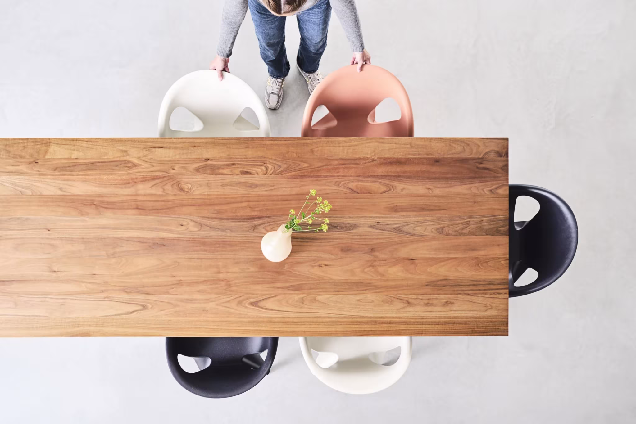 Vista cenital de una mesa de madera rodeada de sillas Bell Chair negras, blancas y salmón