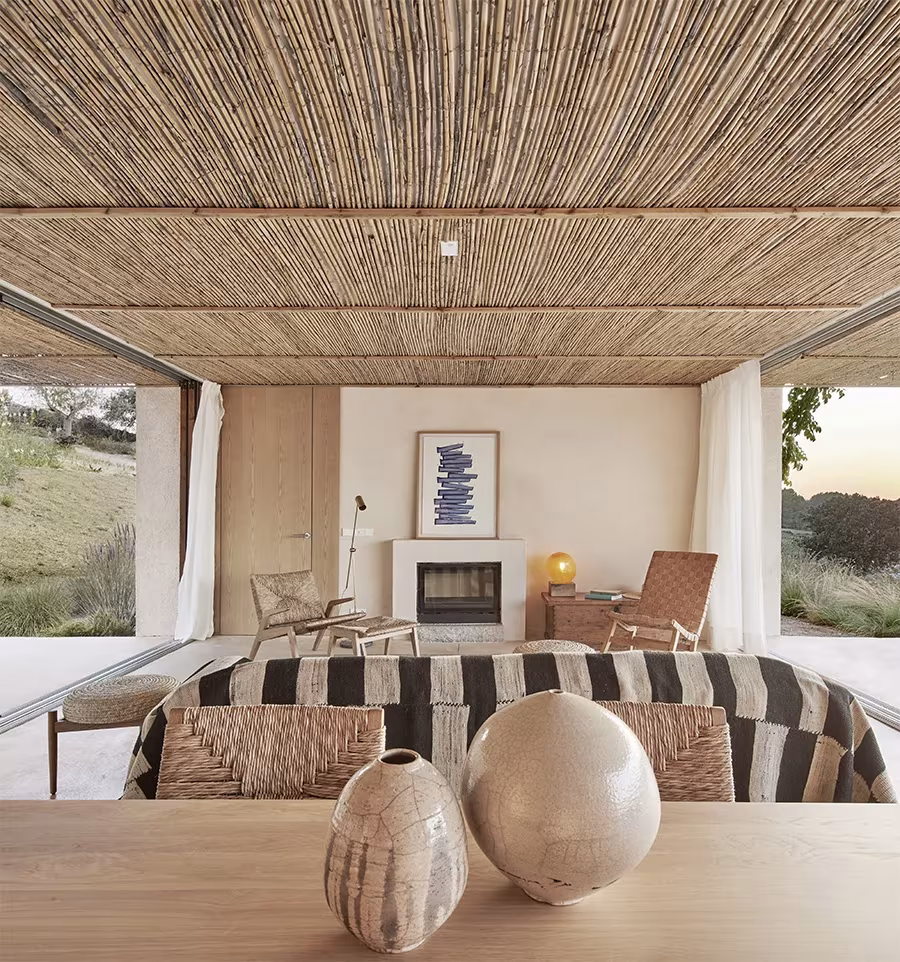 Salón de la Casa Palerm con chimenea, sofá de rayas y dos jarrones de cerámica sobre una mesa de madera