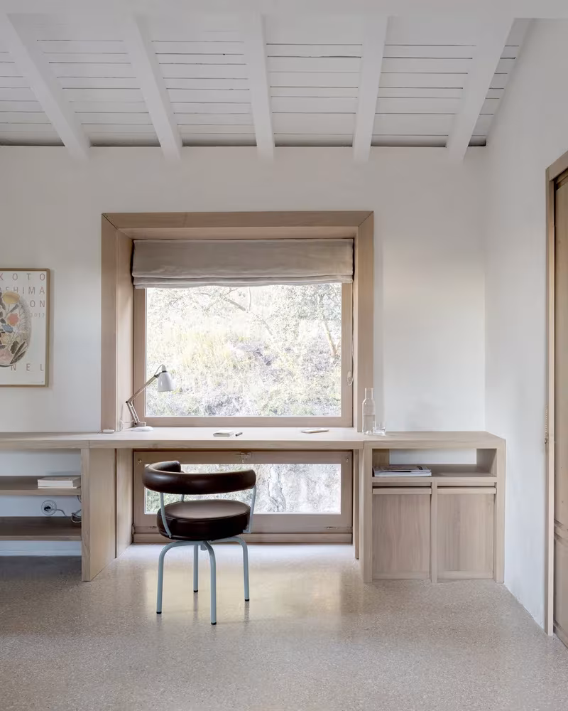 Escritorio empotrado de madera bajo una ventana de ancho marco de roble en la Casa MA