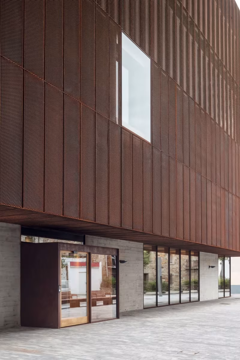 Fachada de chapa de acero corten de la Escuela de Música de Zubiaur con una ventana cuadrada y acceso acristalado