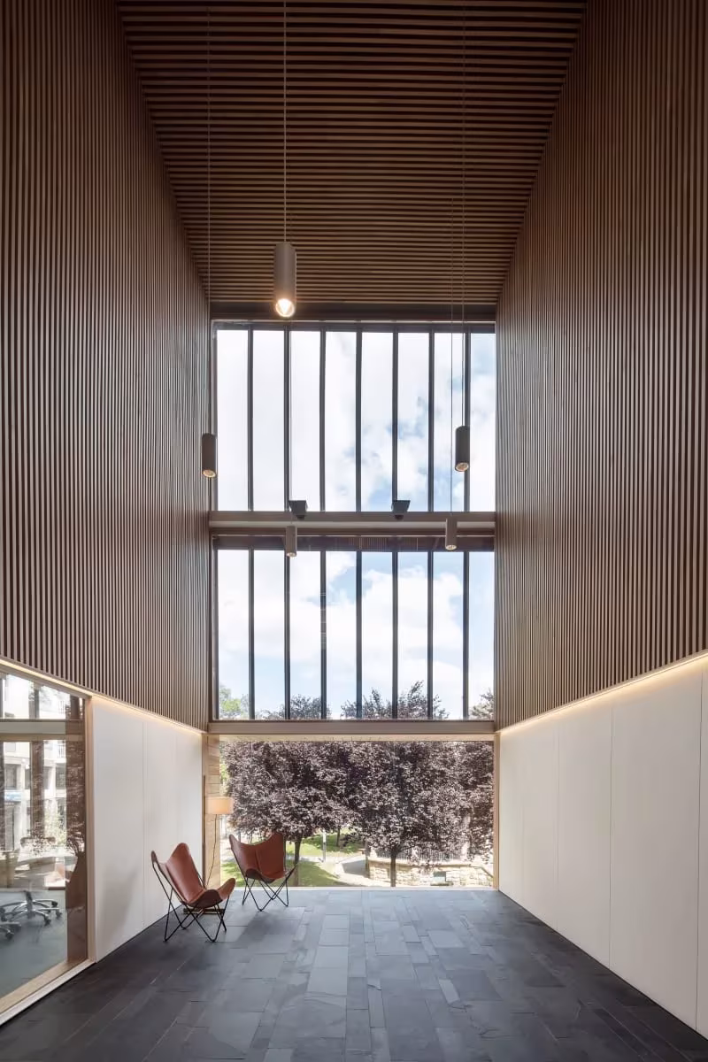 Espacio de doble altura de la Escuela de Música de Zubiaur forrado de listones de madera, con ventanal al jardín