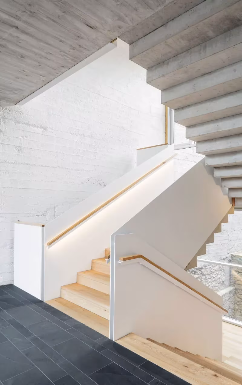 Arranque de la escalera de la Escuela de Música de Zubiaur con peldaños de madera y suelo de pizarra