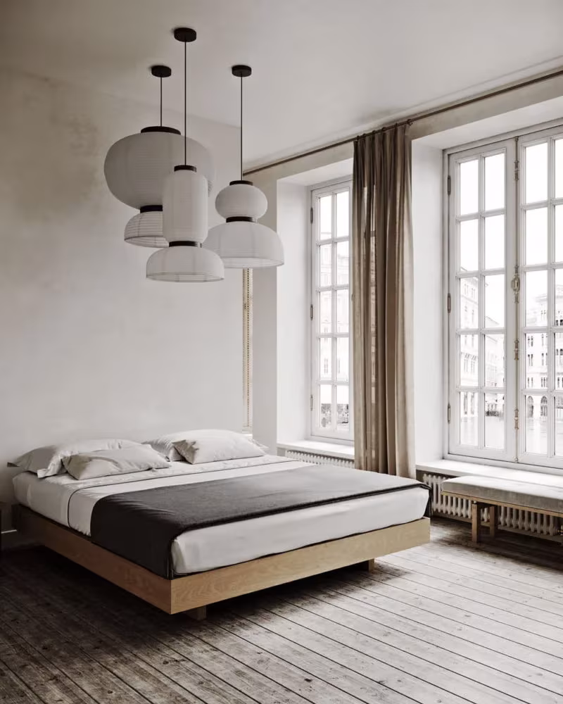 Dormitorio minimalista en Copenhague con cama baja de madera, lámparas de papel colgantes y ventanales