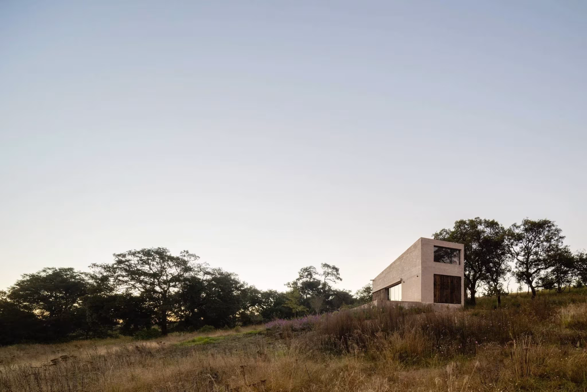 Refugio de Pérez Palacios Arquitectos en Aculco, volumen de piedra en lo alto de una loma con árboles