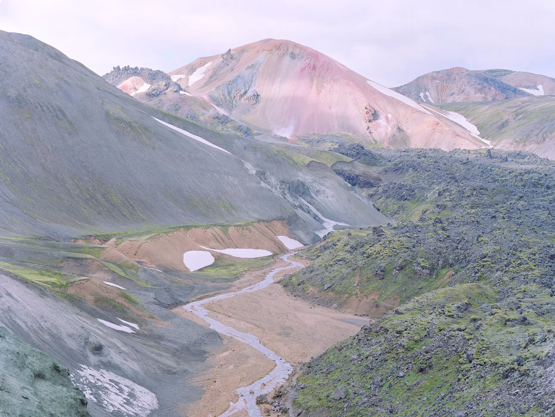 Valle con una montaña rosada al fondo y un arroyo entre laderas de musgo, fotografía de Luca Tombolini