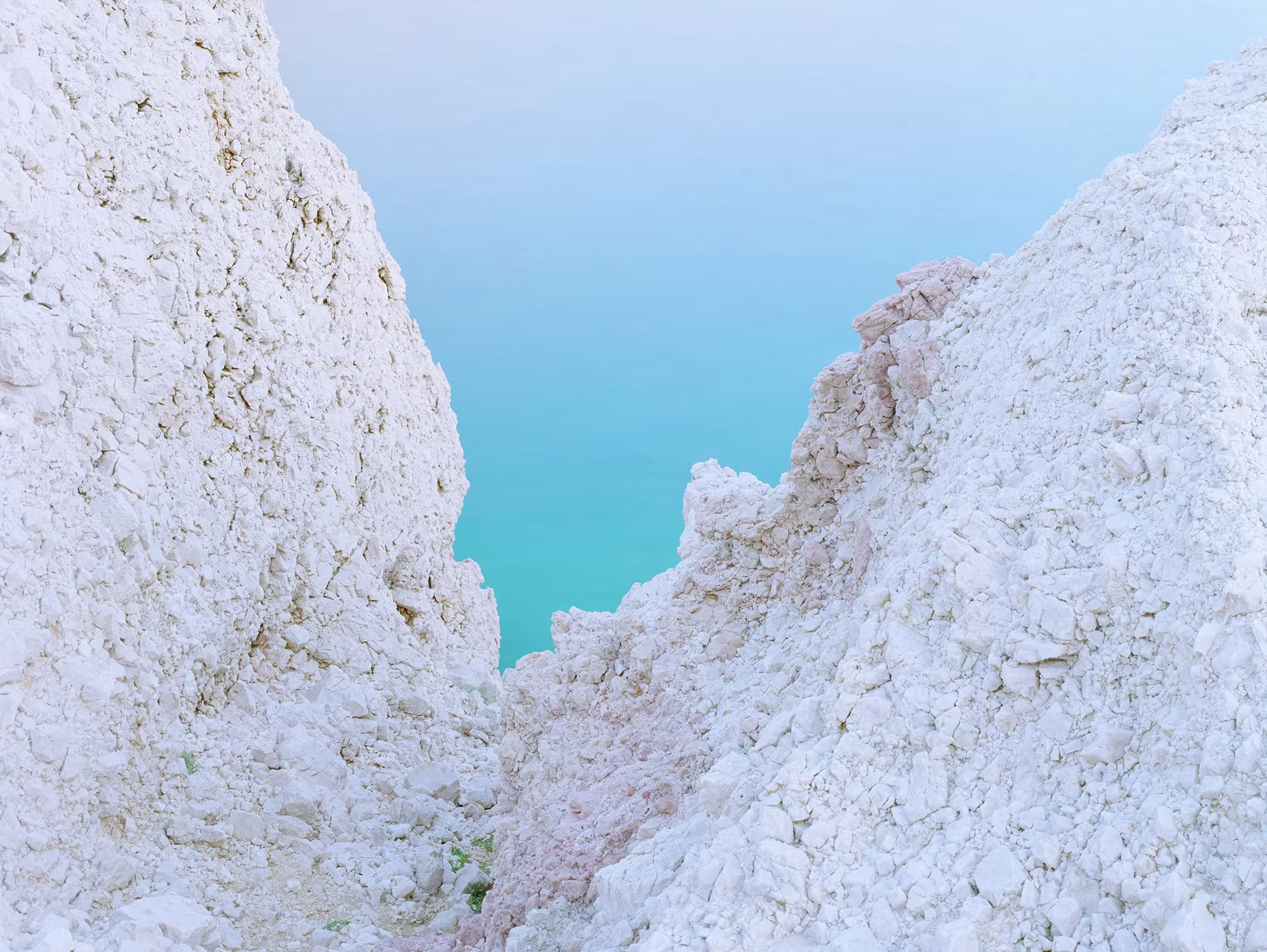 Grieta entre rocas blancas con un agua turquesa al fondo, fotografía de Luca Tombolini