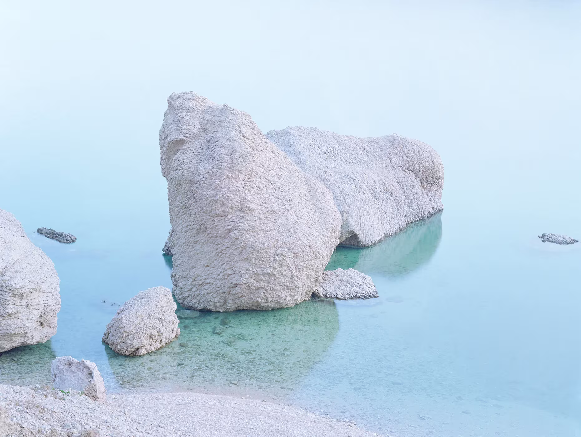 Rocas blancas y redondeadas emergiendo de un agua turquesa muy clara, fotografía de Luca Tombolini