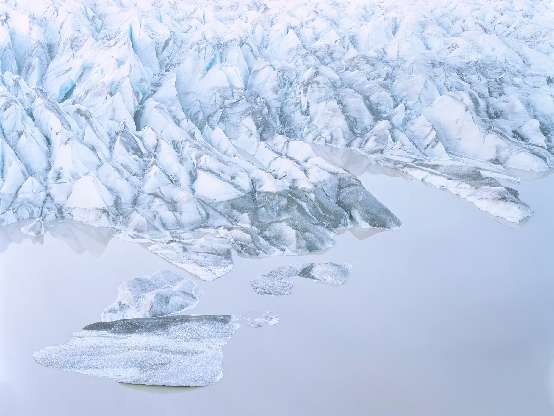 Frente de hielo agrietado y bloques flotando sobre agua en calma, fotografía de Luca Tombolini
