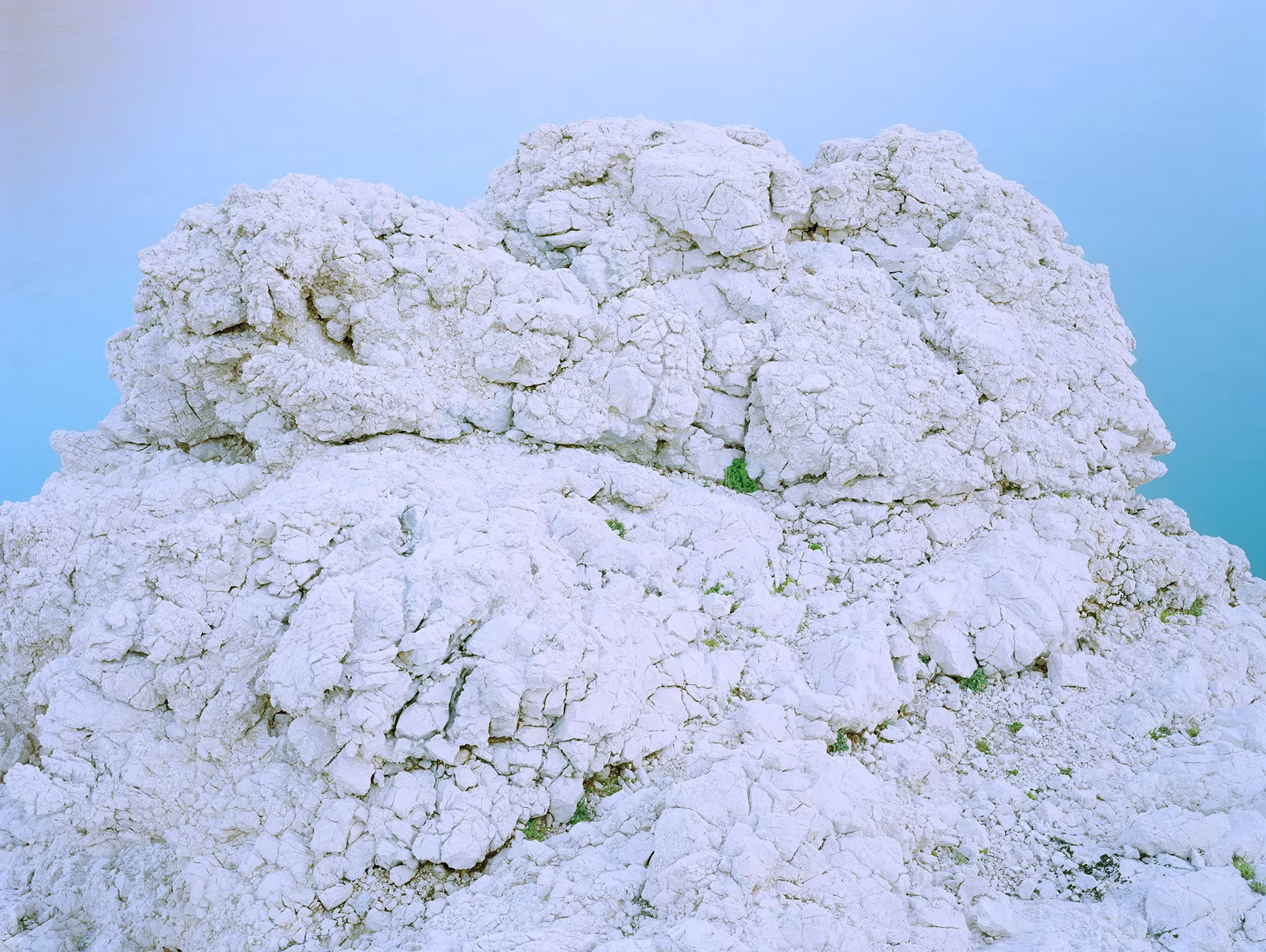 Formación de sal o roca blanca de superficie rugosa ante un cielo azul pálido, de Luca Tombolini