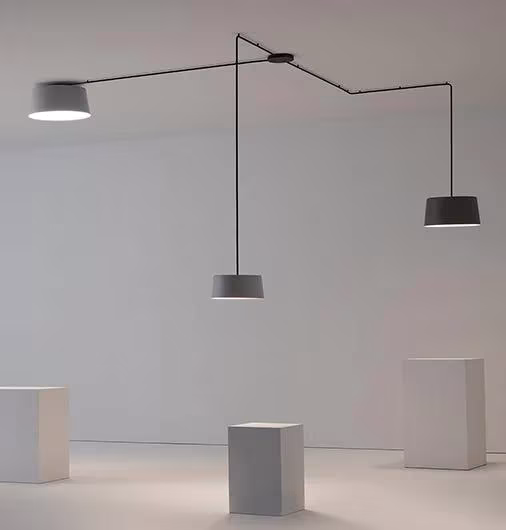 Tres lámparas Tube a distinta altura unidas por cables angulares sobre plintos blancos