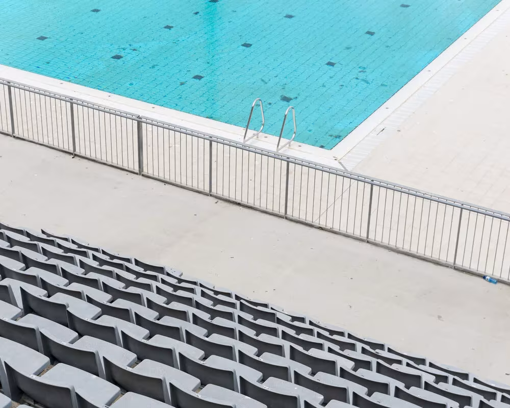 Piscina turquesa con barandilla blanca sobre unas gradas de hormigón, fotografía de Guillermo Santos