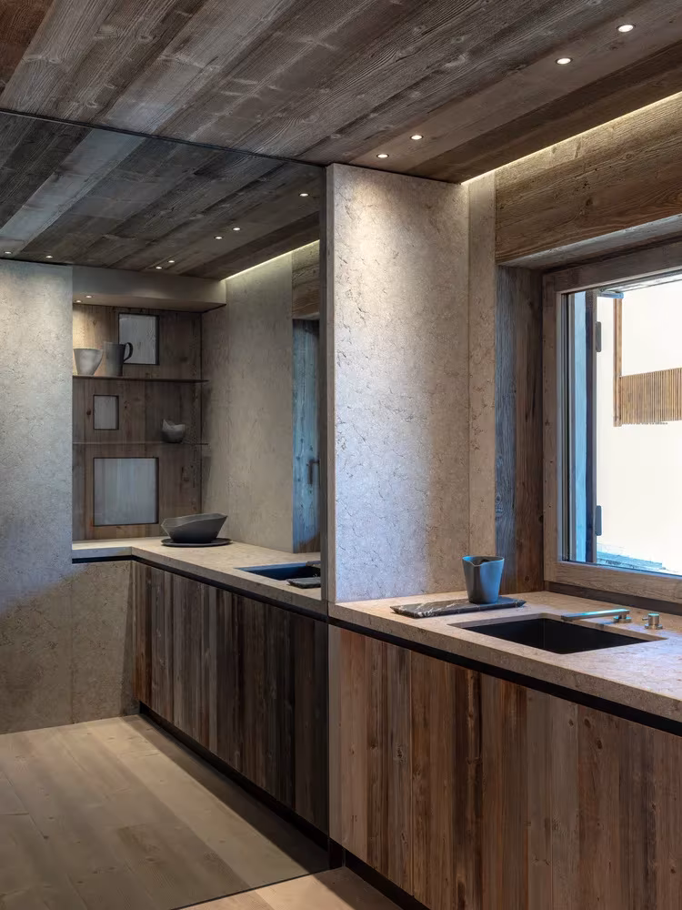 Cocina alargada de Casa Cortina con muebles de madera, encimera clara y ventana lateral