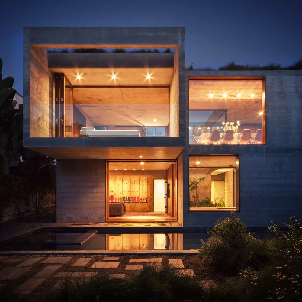 Casa Phoenix al anochecer con las cajas de hormigón iluminadas sobre un estanque, obra de Sebastián Mariscal