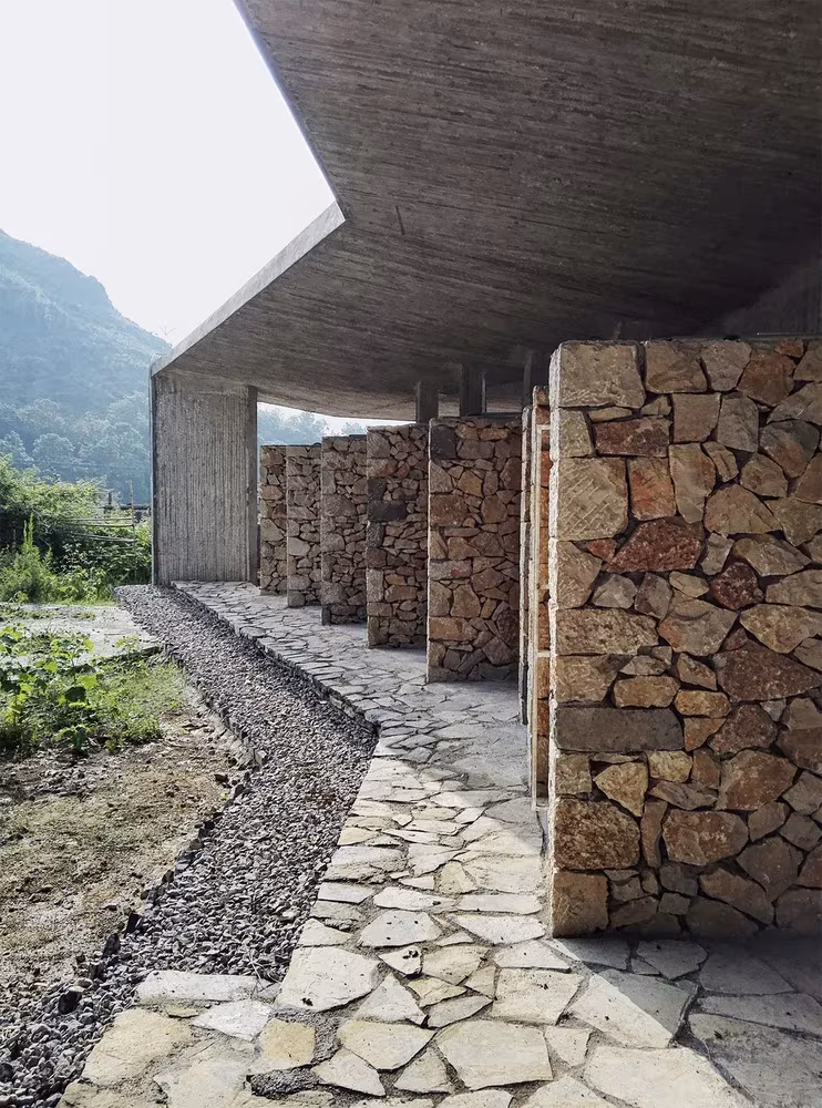 Porche de hormigón con pilares de mampostería de piedra y camino empedrado en el campamento de Pingqiao