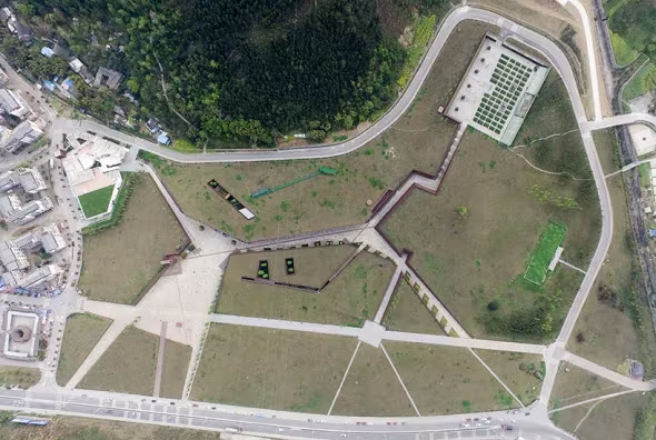 Planta del museo de Beichuan vista desde el aire, con caminos que cortan la cubierta de césped