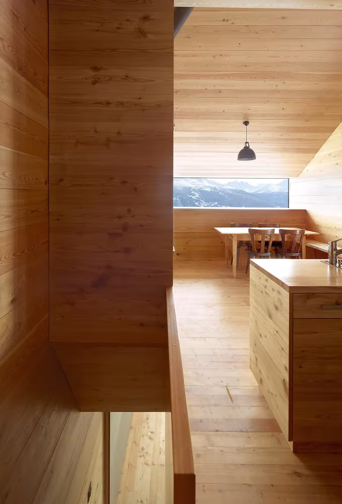 Cocina y comedor de madera vistos desde la escalera, con una ventana corrida en la Casa Gaudin
