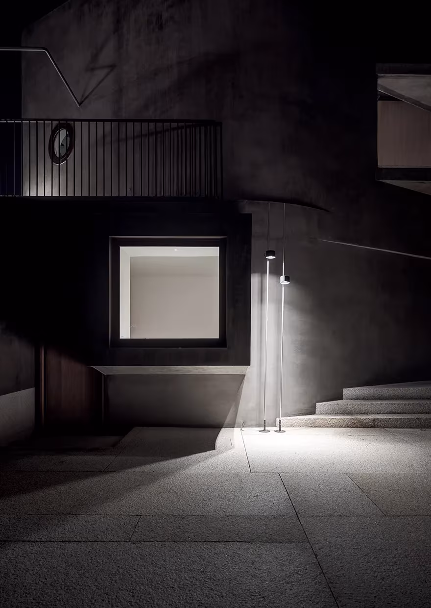La Grintosa de Stefania Stera de noche, volumen oscuro con una ventana iluminada y escalera exterior