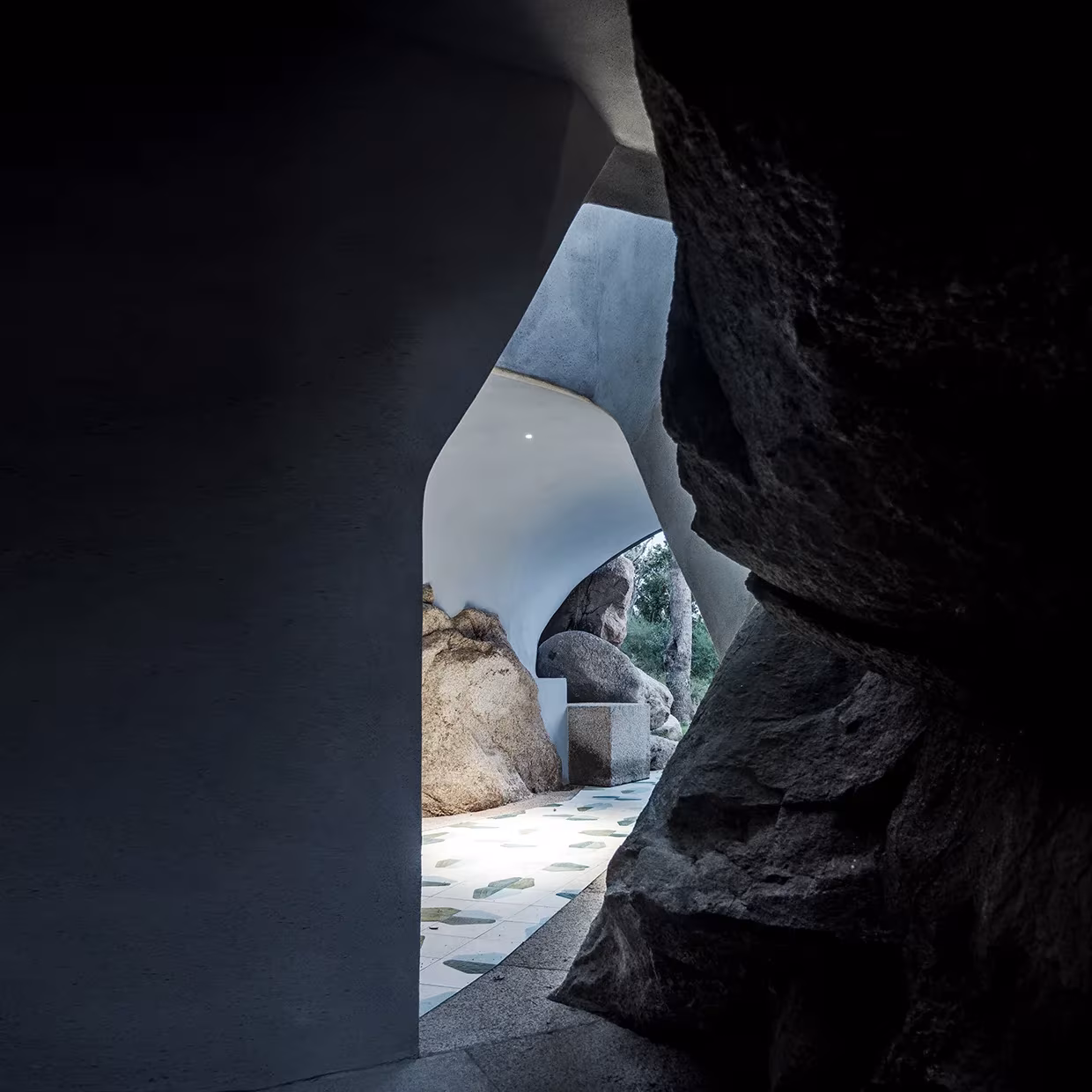 Abertura orgánica entre grandes rocas de granito que da paso a un patio de baldosas en La Grintosa