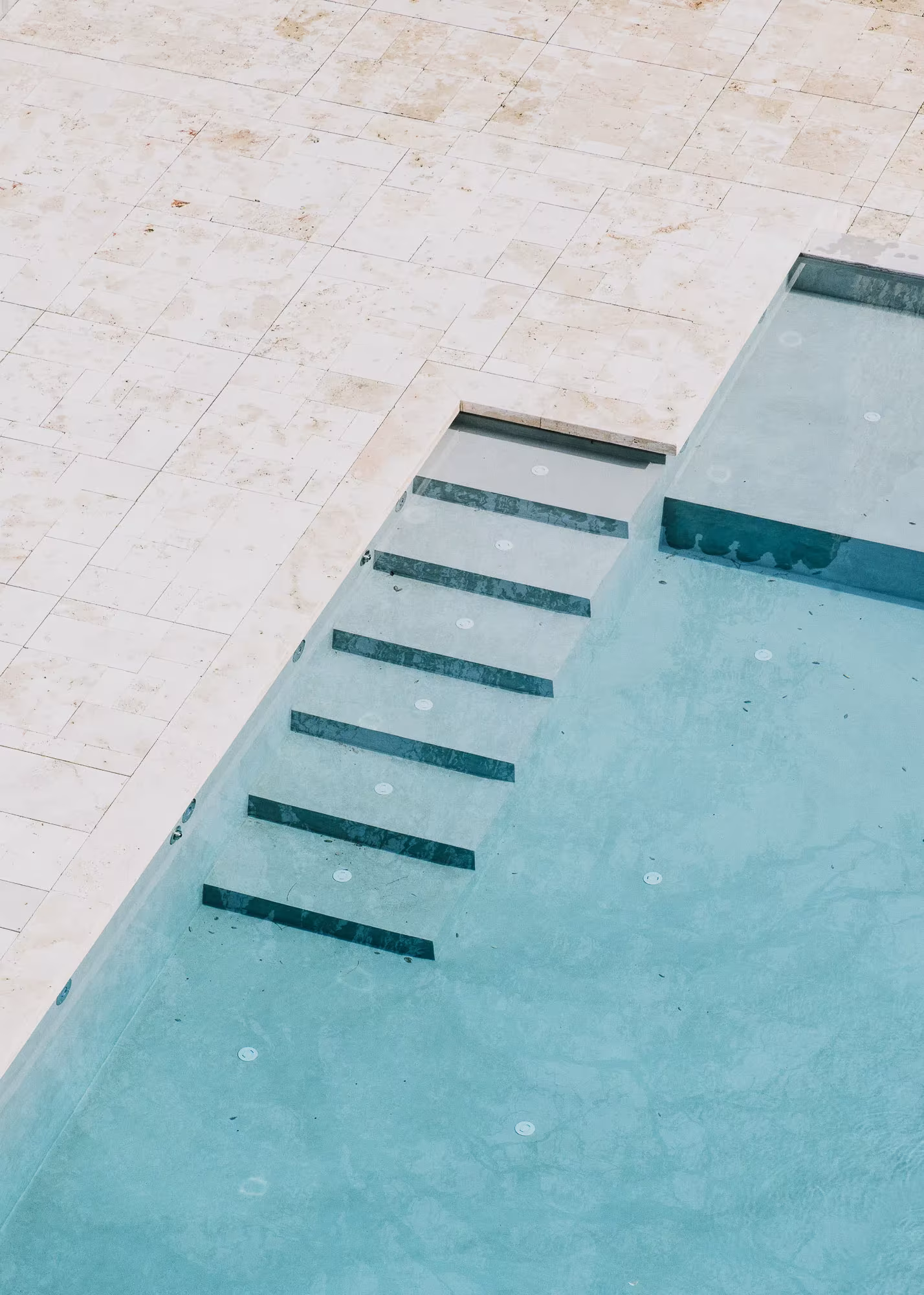 Vista cenital de una piscina de piedra clara con escalones sumergidos en Peratallada
