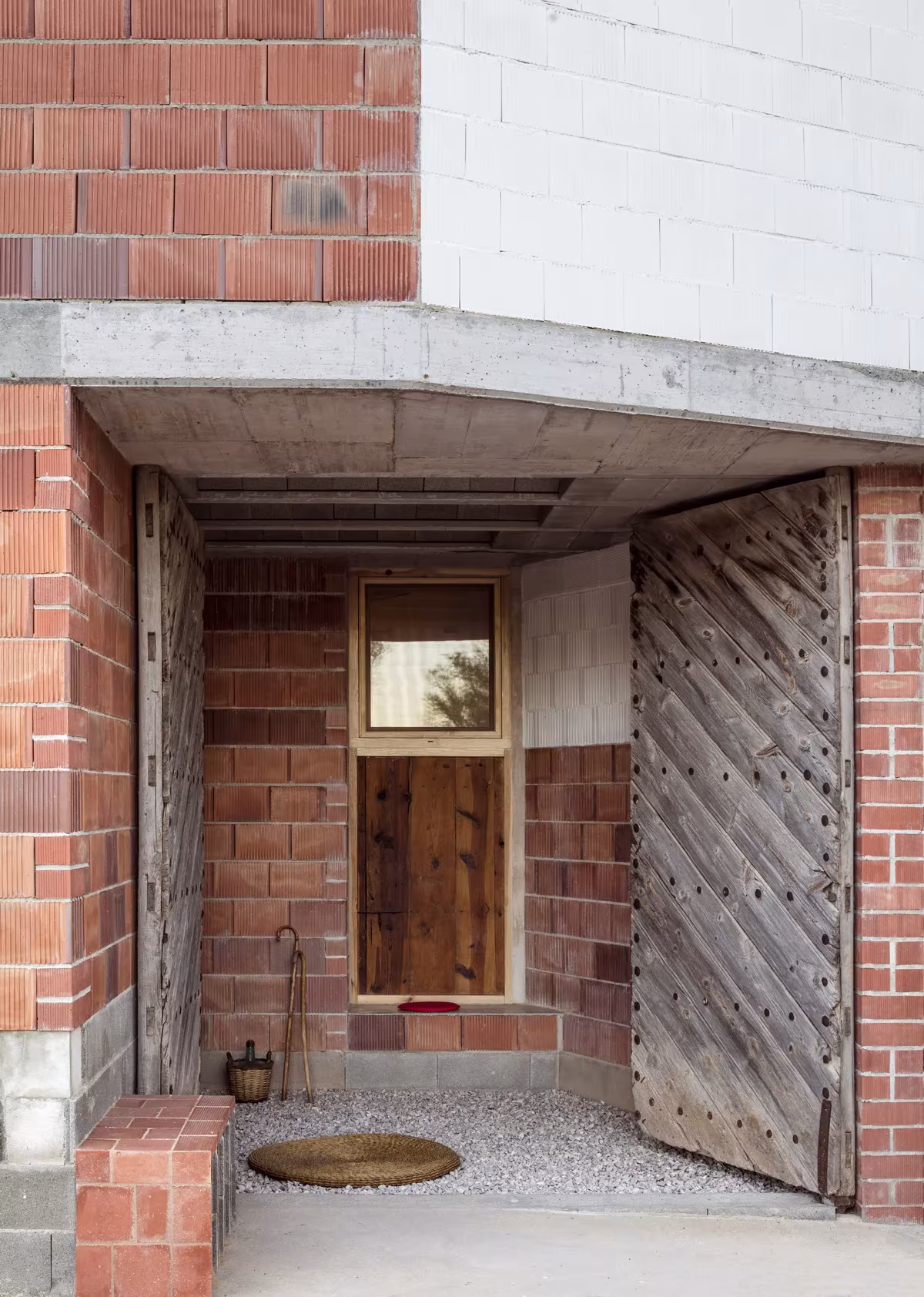Entrada con puerta de tablas de madera y hornacina bajo un porche de hormigón en la Casa en Tres Primaveras