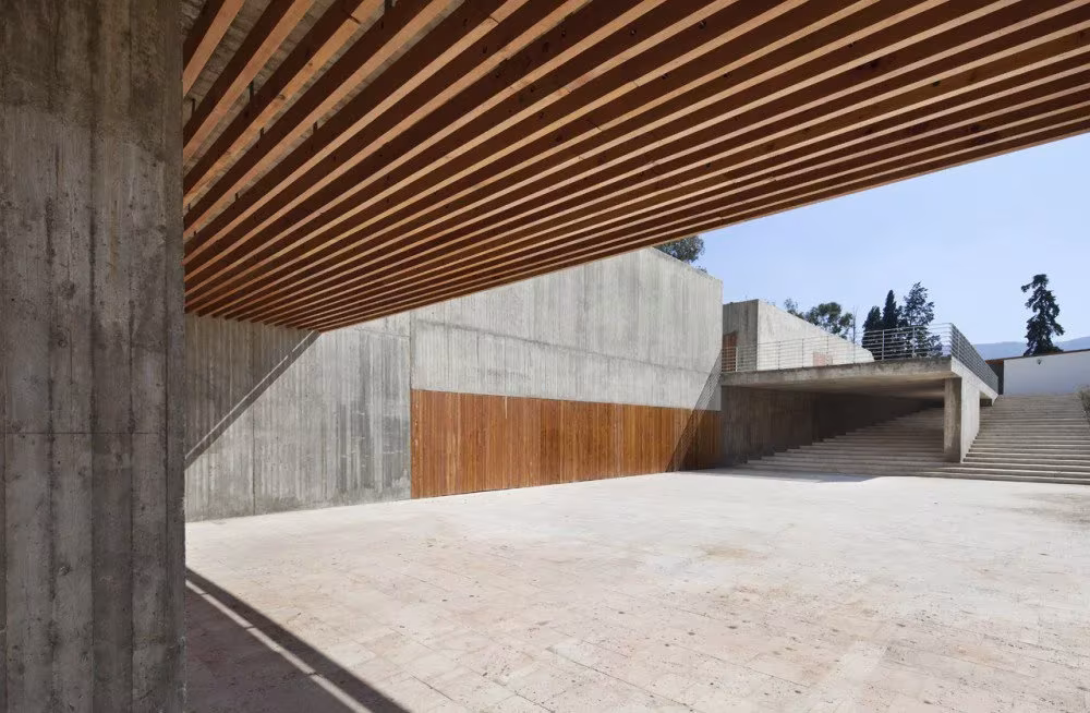 Cubierta de lamas de madera sobre un patio pavimentado con muros de hormigón en el Museo de Volubilis