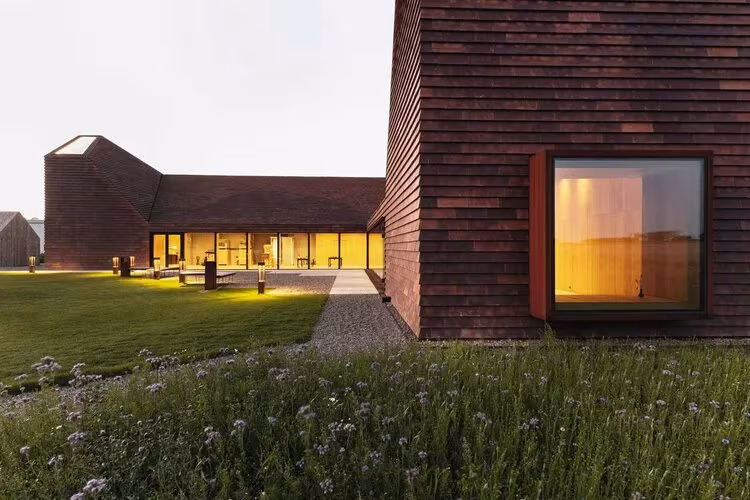 Ala del Kornets Hus con gran ventana de esquina iluminada y jardín en Dinamarca