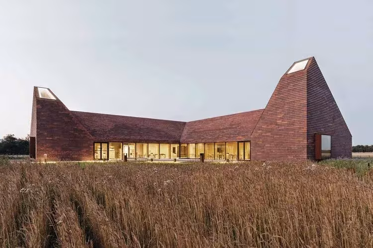 Kornets Hus en forma de L al anochecer, con lucernarios en los dos volúmenes de ladrillo