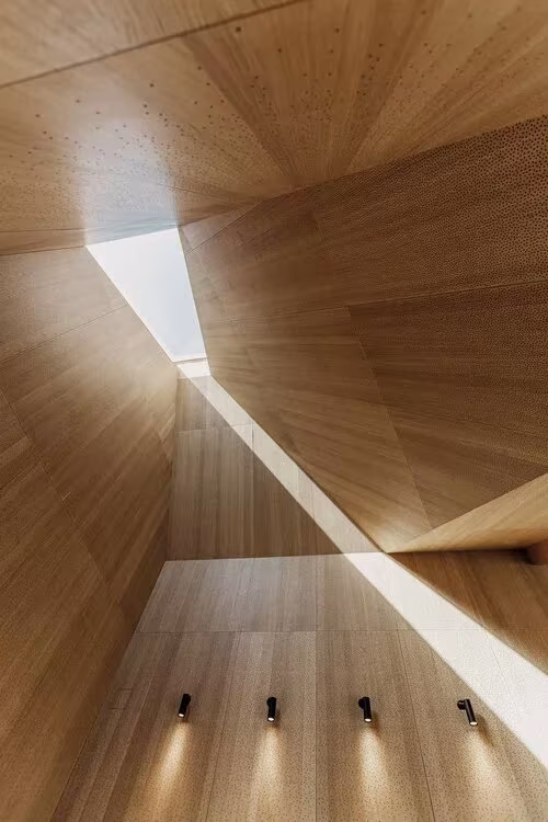 Lucernario inclinado que reparte luz sobre paramentos de madera en el Kornets Hus