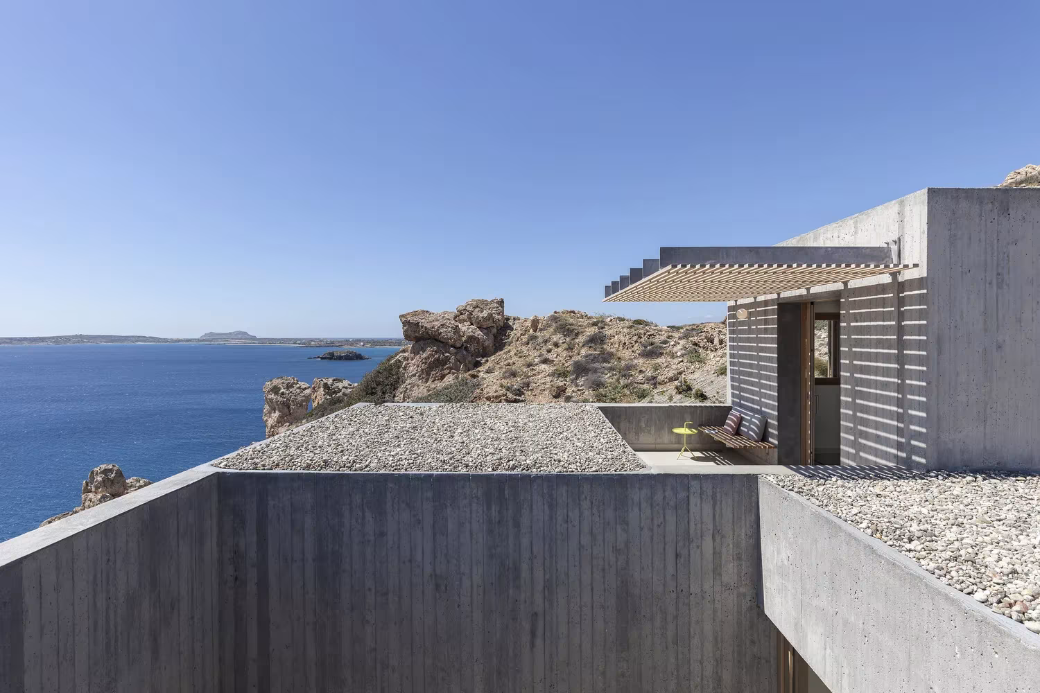 Cubierta de grava y celosía de madera de la Casa Patio con la costa de Kárpatos al fondo
