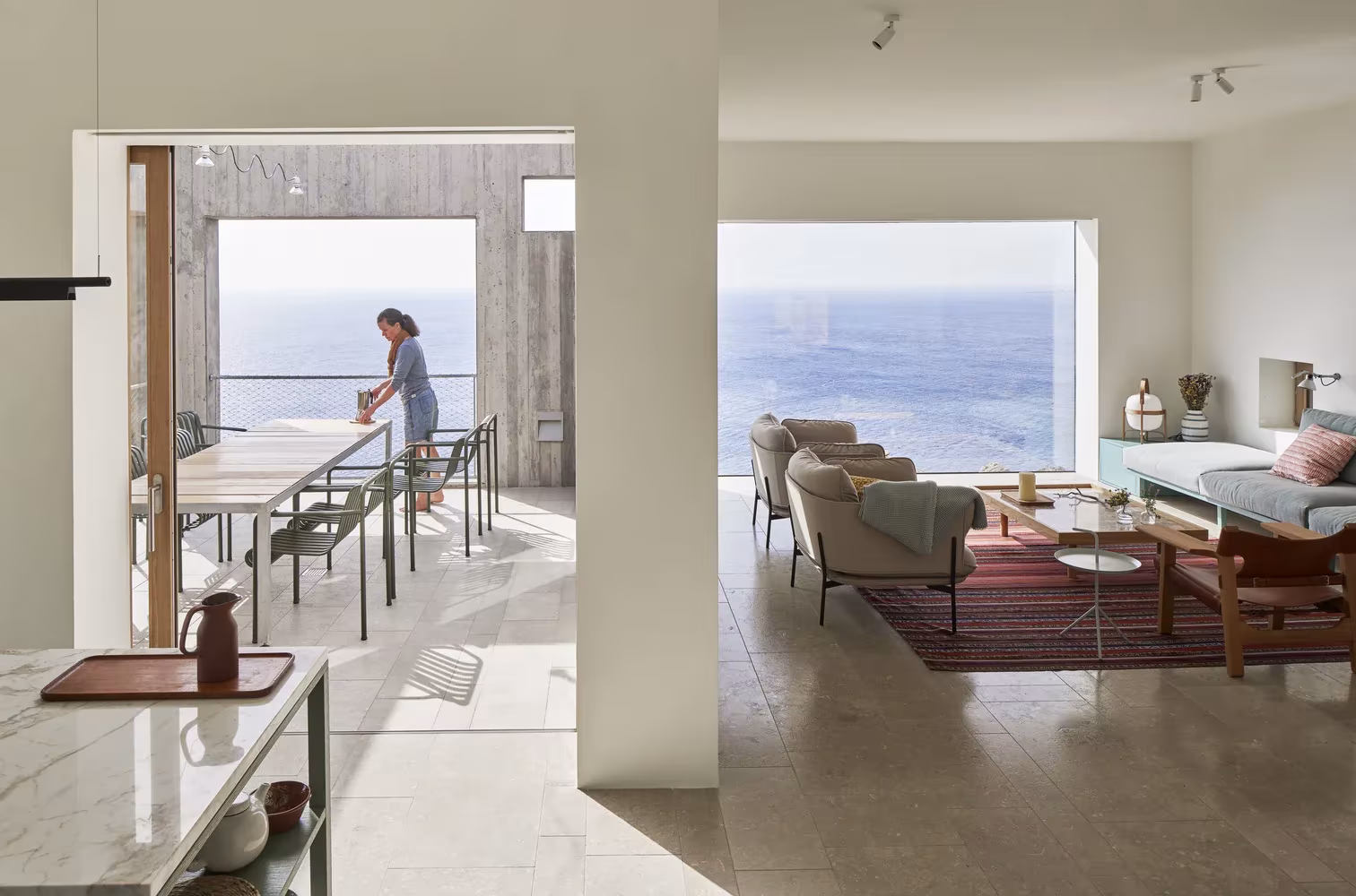Estancia continua entre cocina, comedor y salón con vistas al mar en la Casa Patio de OOAK Architects