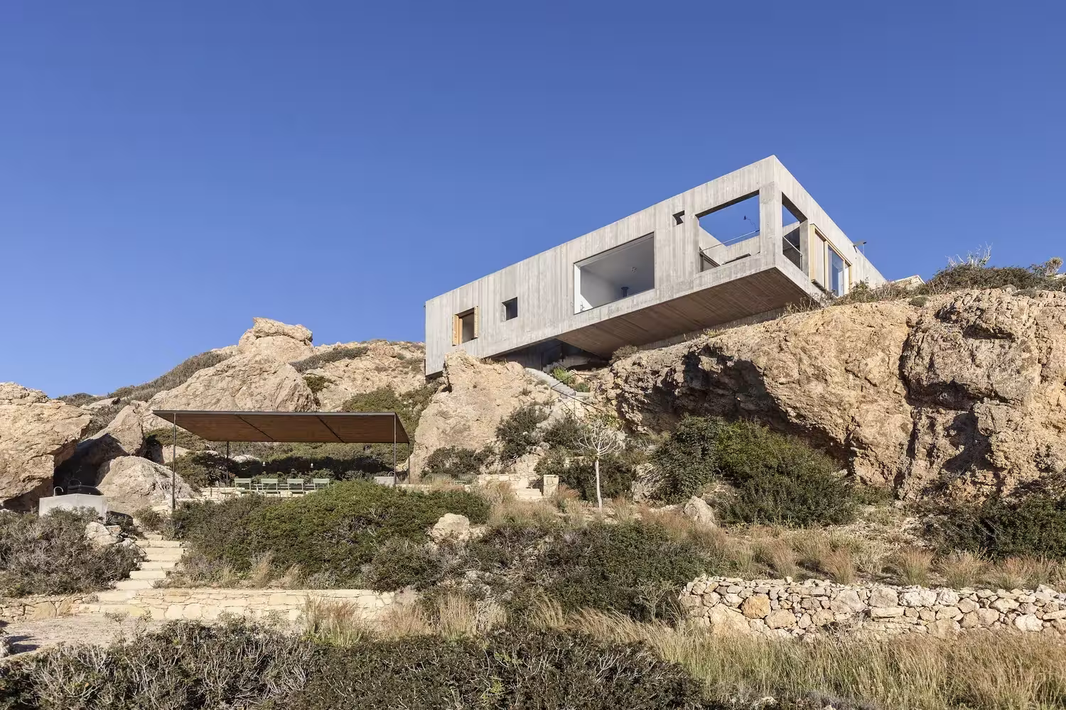 Volumen superior en voladizo de la Casa Patio sobre el roquedo y senda de piedra seca