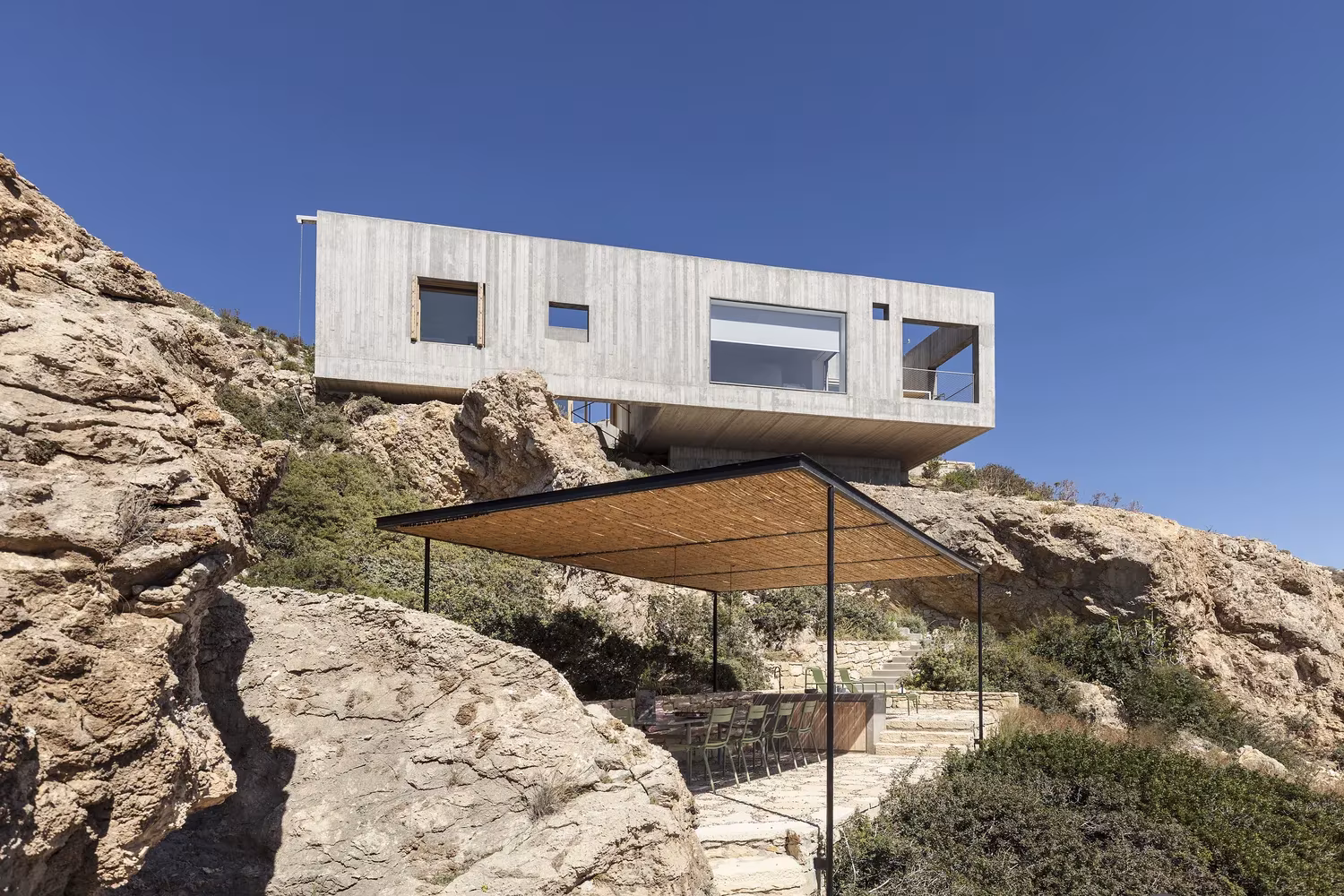 Casa Patio de OOAK Architects en voladizo sobre la roca con una pérgola de madera, en Kárpatos