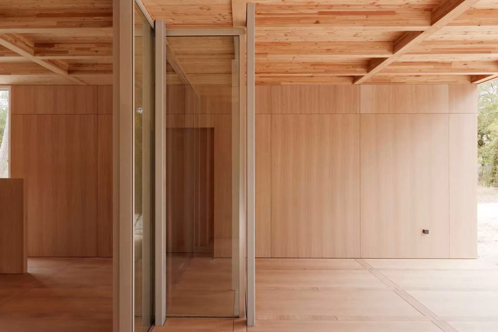 Interior de la Maison en Bois con techo artesonado de madera, paneles de pino y una gran puerta corredera
