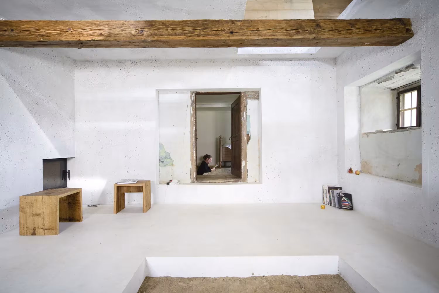 Cubo de hormigón blanco con vigas de madera antiguas y mobiliario de madera maciza en la granja bávara