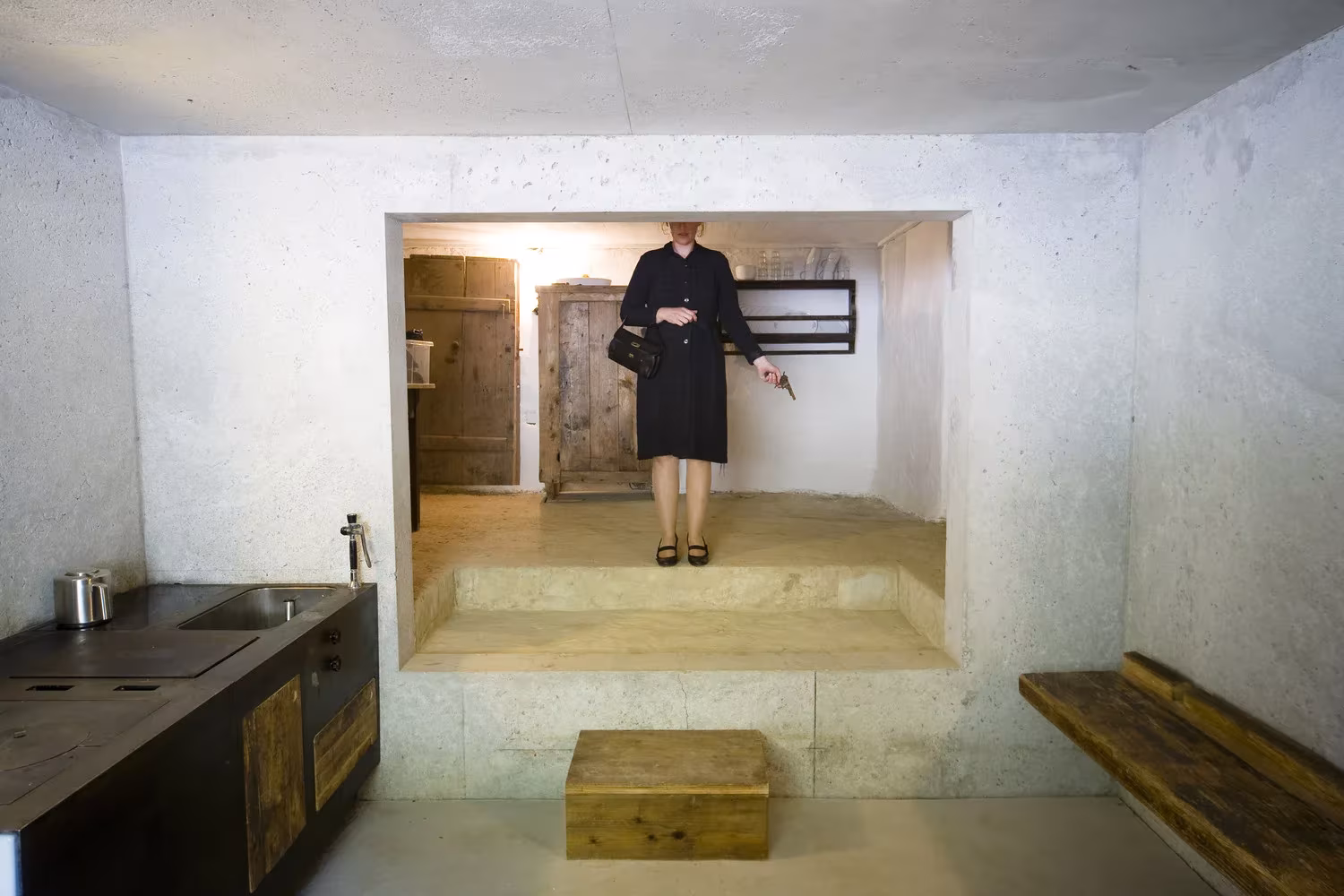 Hueco de hormigón con un banco de madera y cocina negra en la granja Birg mich, Cilli!