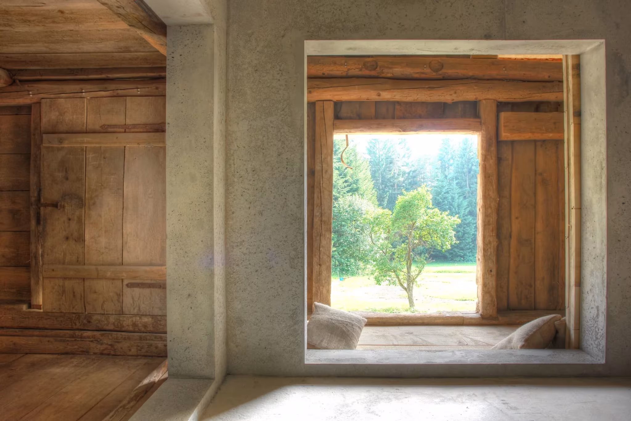 Ventana de hormigón con asiento que enmarca un manzano en el interior de la granja de Peter Haimerl