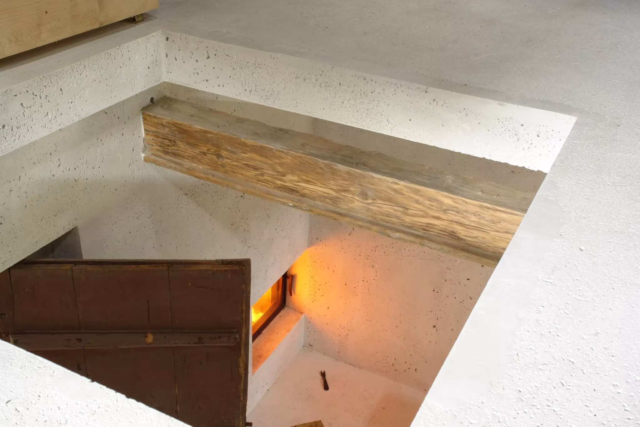 Vista cenital de un hueco de hormigón con viga de madera antigua y chimenea encendida en la granja